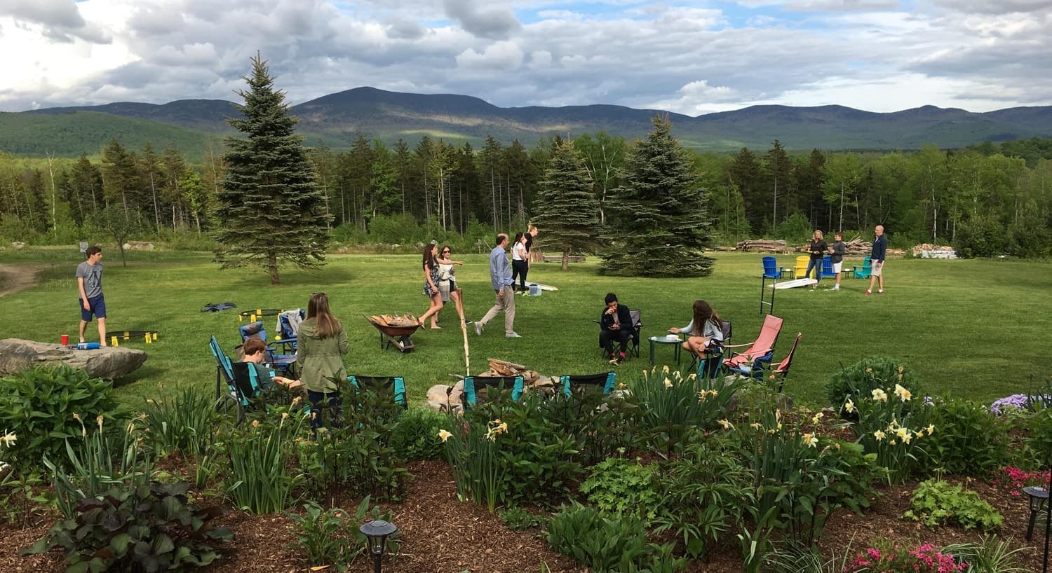 A relaxed outdoor gathering with people enjoying a garden and mountain view.