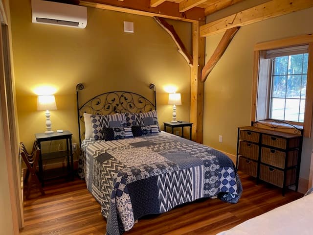 Cozy bedroom with a patterned quilt, two lamps, and wooden accents.