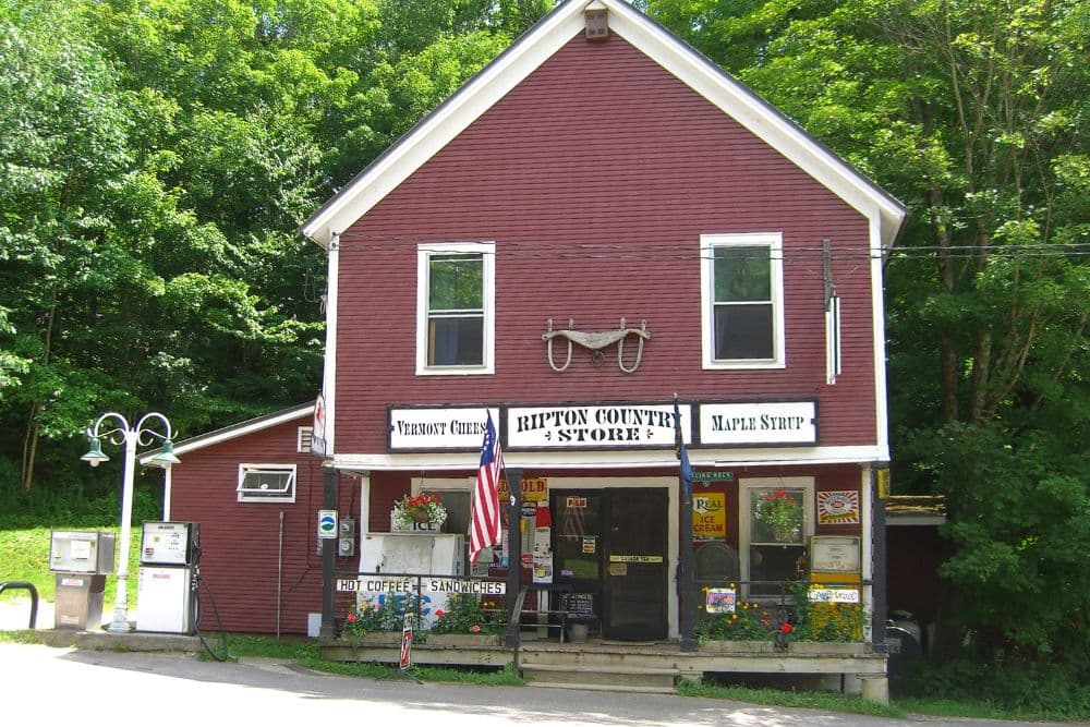 A quaint red general store surrounded by lush green trees.