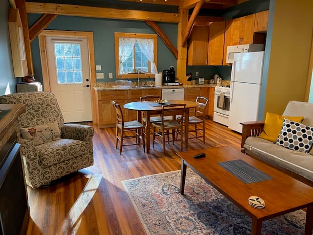 Cozy kitchen and living area with wooden beams, a dining table, and comfortable seating.
