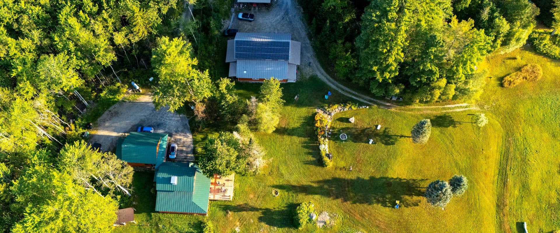 Aerial view of a wooded property featuring several buildings and grassy areas.