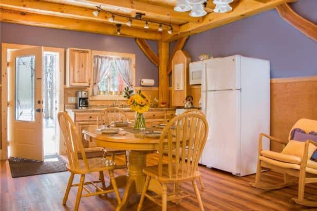 Hemlock Hideaway cabin's kitchen with window, glass door, wood floor and cabinetry, round dining table with chairs